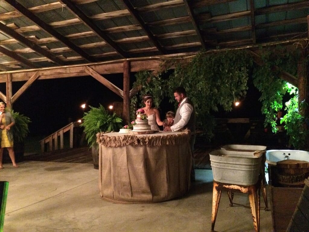 Burdoc Farms Wedding DJ | Crofton KY Wedding DJ & MC 9 Bride and groom cutting a multi-tiered wedding cake at an outdoor rustic reception