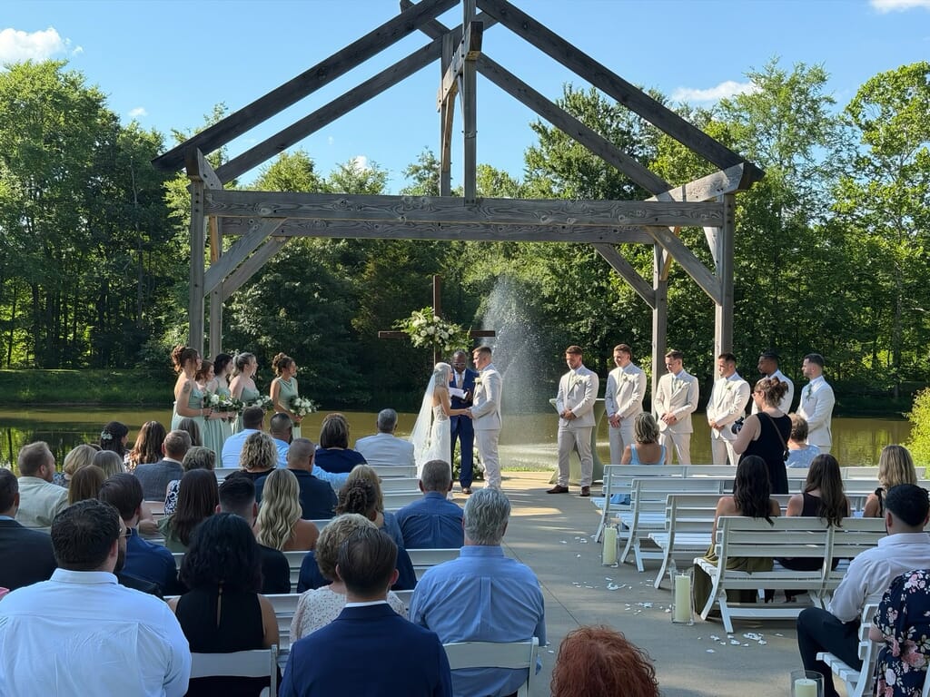 Burdoc Farms Wedding DJ | Crofton KY Wedding DJ & MC 7 Outdoor wedding ceremony under a wooden timber frame with a bride and groom, wedding party, and seated guests