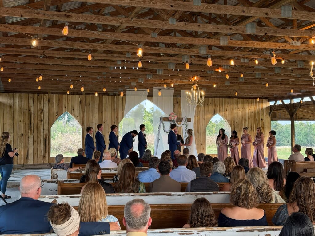 Burdoc Farms Wedding DJ | Crofton KY Wedding DJ & MC 5 Wedding ceremony in a rustic wooden barn with guests seated in pews, facing the bride, groom, and wedding party at the altar