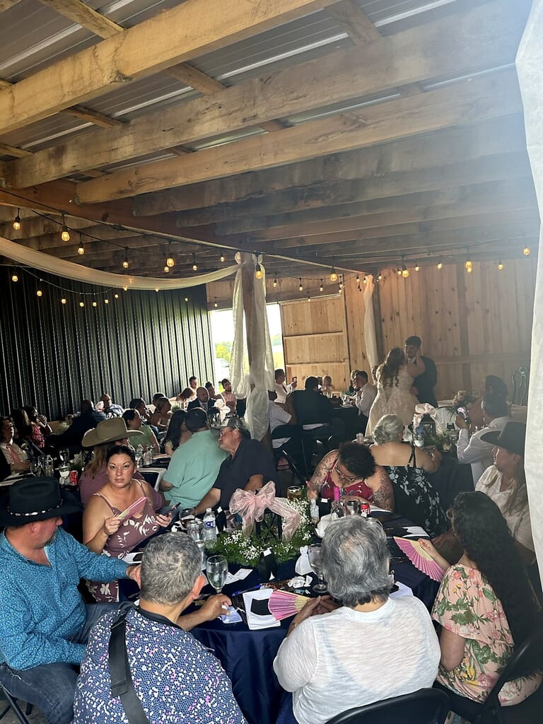 Wedding DJ Princeton Ky 7 Guests seated at tables in a rustic barn during a wedding reception, with a bride and groom dancing in the background