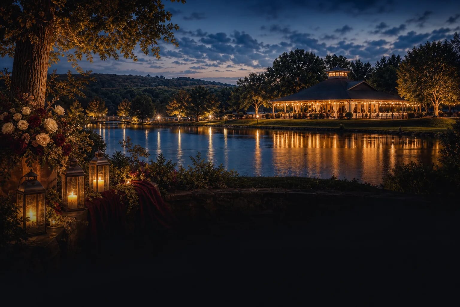 Lit lanterns and floral arrangements by a tranquil lake, with an illuminated pavilion reflecting on the water at dusk.