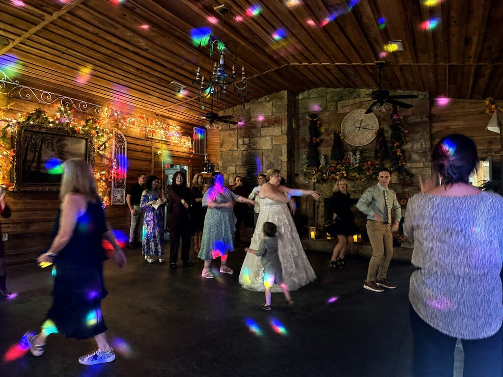 Wedding DJ Princeton Ky 11 A bride and guests dance in a rustic room with wood walls and colorful disco lights