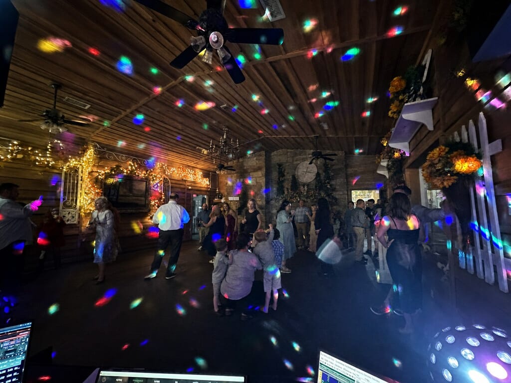 Wedding DJ Princeton Ky 13 People dancing in a rustic room illuminated by colorful disco lights