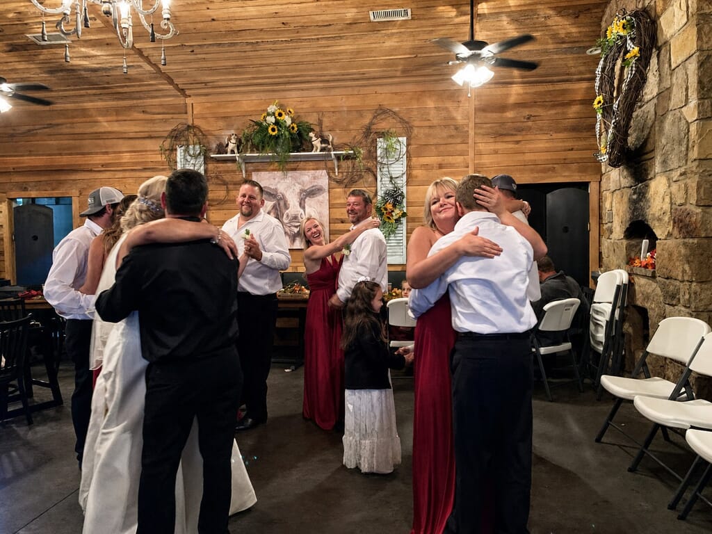 Wedding DJ Princeton Ky 15 Wedding guests and family in formal attire hugging and celebrating in a rustic wood-paneled room