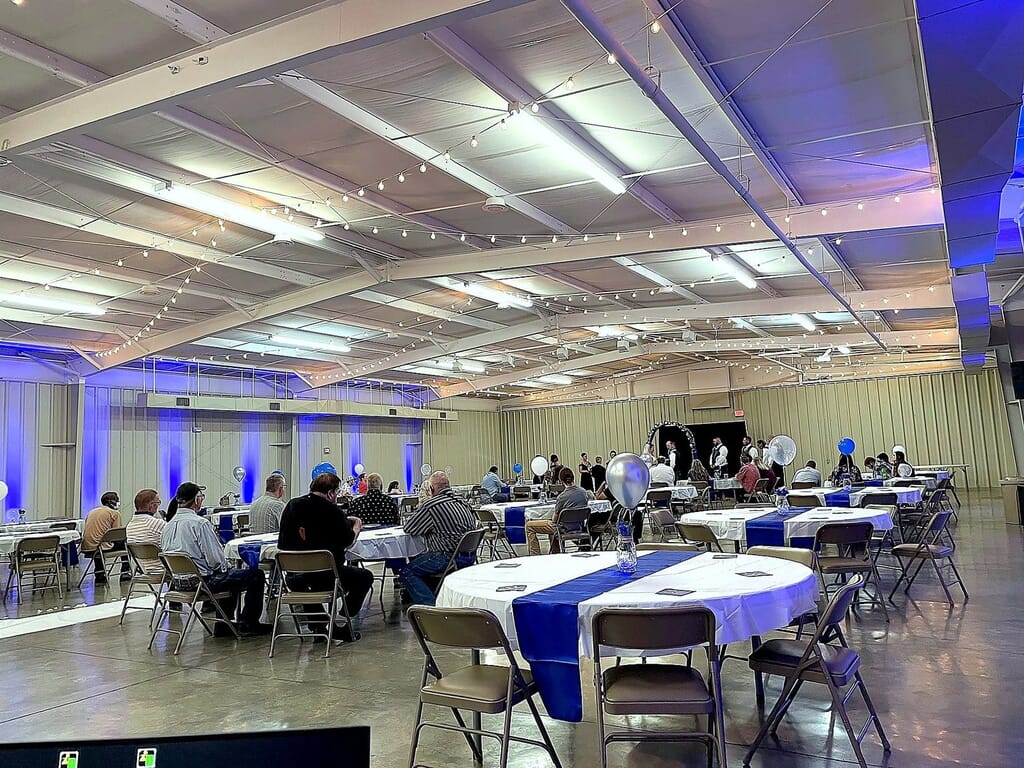 Madisonville Kentucky Wedding DJ 19 Event space with guests at round tables with blue and white linens under string lights and blue accent lighting.