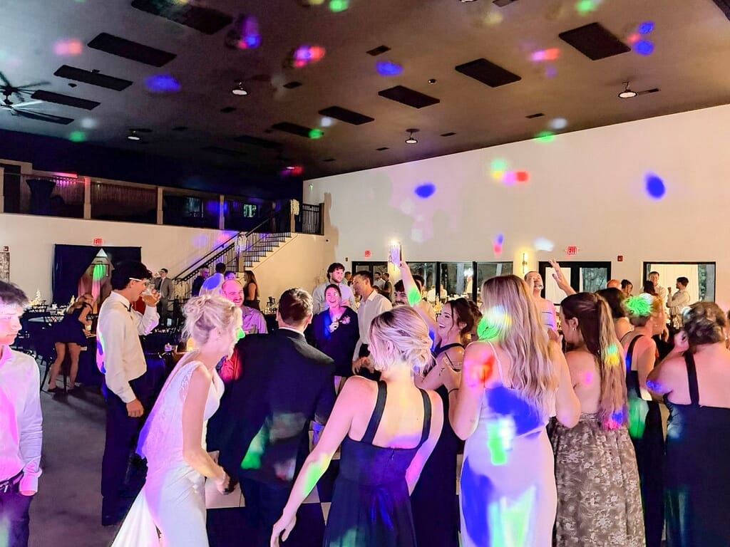 Gallery - Highbanks Wedding & Events Real Weddings 10 Guests in formal attire dancing under colorful lights at a Highbanks wedding reception.