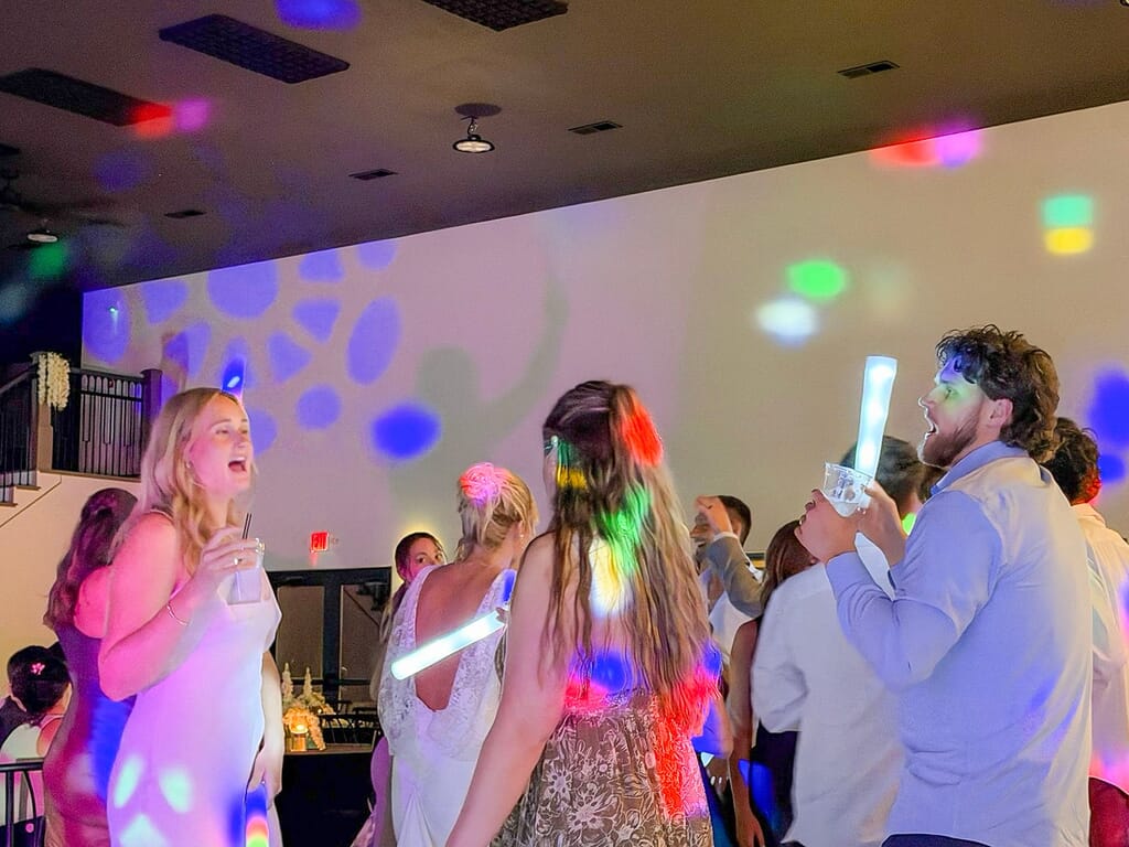 Gallery - Highbanks Wedding & Events Real Weddings 11 Wedding guests dancing with foam glow sticks under colored lights at Highbanks.